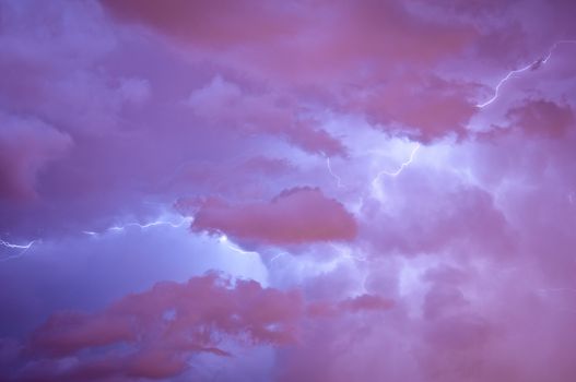 Bright dramatic lightening stretched across the night sky over a cities ambient orange glow of lights giving it unique colors