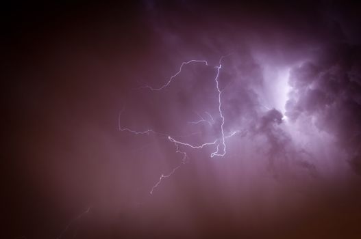 Bright dramatic lightening stretched across the night sky over a cities ambient orange glow of lights giving it unique colors