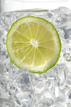 glass of ice cubes with a lemon slice on white background