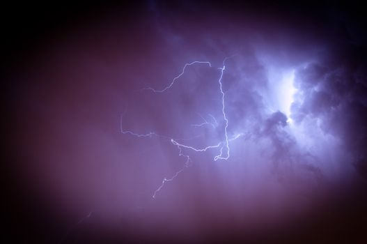 Bright dramatic lightening stretched across the night sky over a cities ambient orange glow of lights giving it unique colors