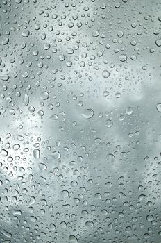 background image of rain drops on glass with a bright sky behind