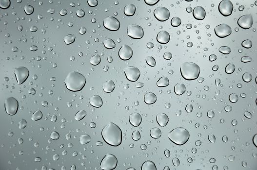 background image of rain drops on glass with a bright sky behind