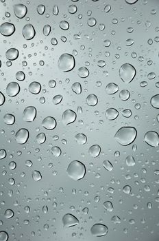 background image of rain drops on glass with a bright sky behind