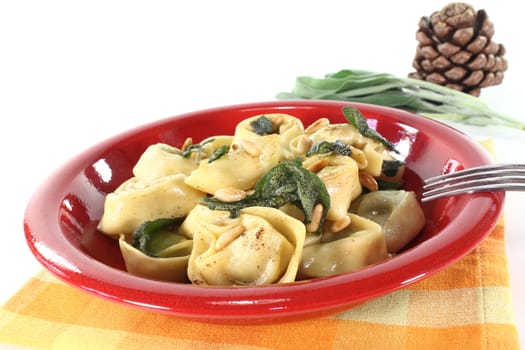 stuffed tortellini with sage butter and pine nuts on a light background