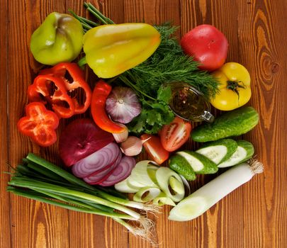 Ingredients of Vegetable Salad with Tomato, Cucumber, Onion, Leek, Dill, Parsley and Olive Oil top view on Wooden background