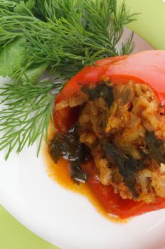 Stuffed Red Bell Pepper Filled with Rice, Meat, Onion and Parsley close up on white plate