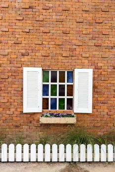 Colorful glass window on brick wall.