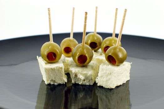 Olives and cheese on black dish