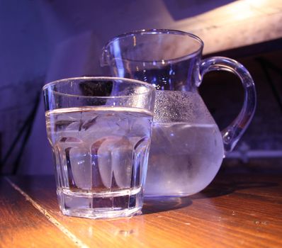 Carafe and glass with cold drink on the wooden table