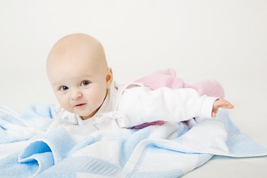 lovely blue-eyed baby with blue towel on the floor