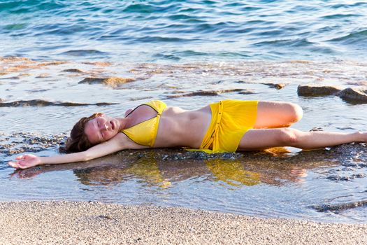 Fatigue women at the beach in yellow swimsuit