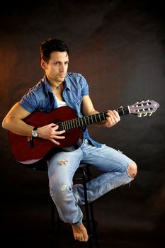 Serious male model with guitar sitting