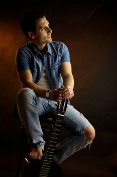 Serious male model with guitar thinking