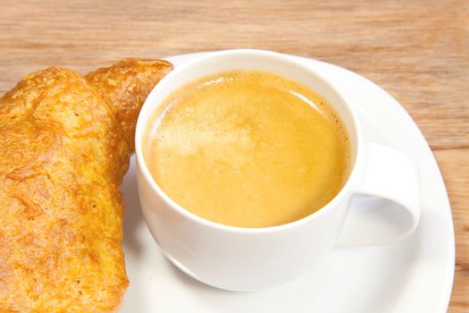 A cup of coffee and one croissant