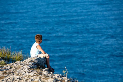 Young kid watching the Black Sea, He is high on the rocks.