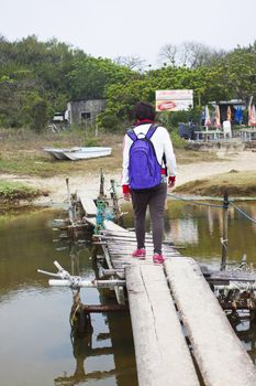 Asian woman walking along a wooden bridge