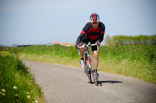 Man on road bike riding down open country road.