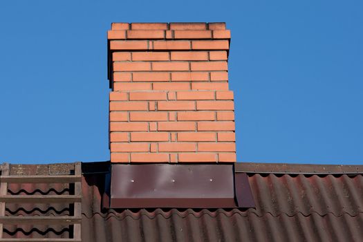 Rricks chimney on the dark  metal-sheet roof
