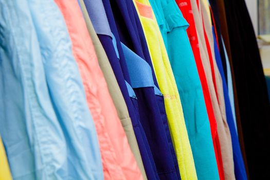 a lot of bright children's clothing on a hanger in the store