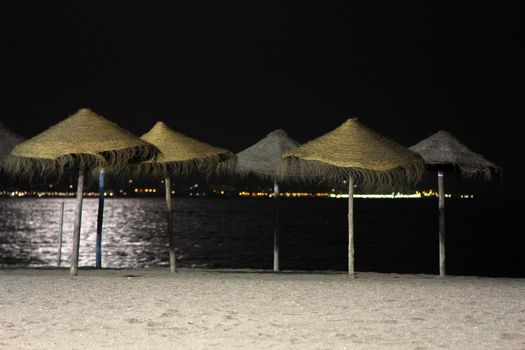 Straw umbrellas at night at the beach