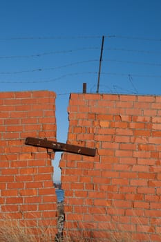Red brick wall with rusty barbed wire