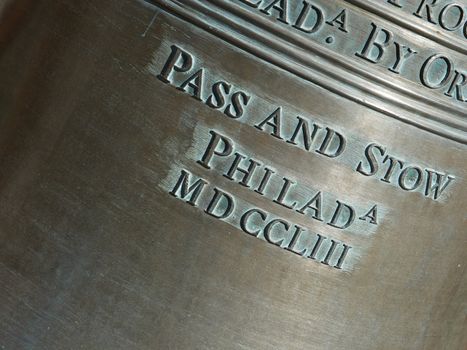Closeup shot of the lettering on a replica of the Liberty Bell. Focusing on the words "Pass and Stow".
