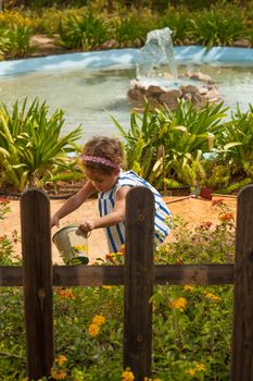 A small girl having fun watering the plants