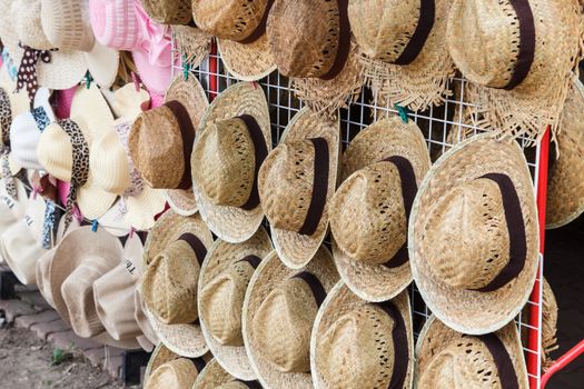 Many straw hats hang on wall.