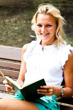 Beautiful and young woman reading a book in the park
