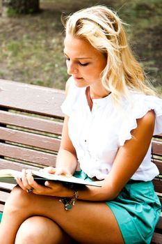 Beautiful and young woman reading a book in the park