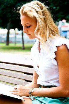 Beautiful and young woman reading a book in the park