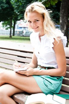 Young and beautiful female student preparing for exams in the park