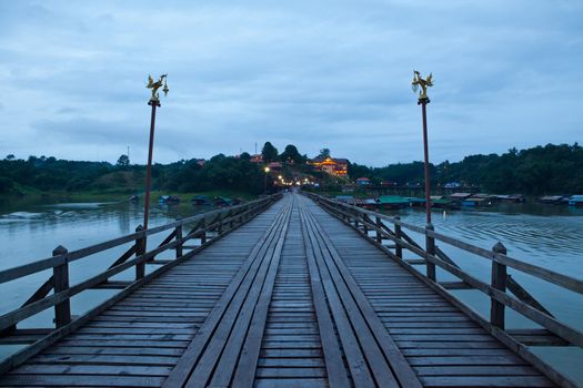 Wood bridge at night with river and mountain in Kanchanaburi Thailand