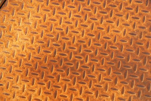 Background of a rusted manhole cover with a repetitive herringbone pattern
