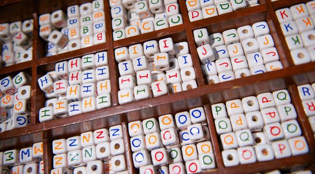 Wooden tray keeps white ceramic beads with the alphabet on them organized