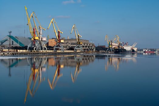 Harbor in sunshine winter day with crane reflection on water