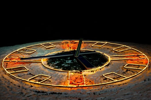 An outdoor clock  with the lights in  the winter night