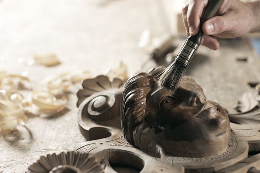 Close Up of carpenter apply varnish to a wooden sculpture