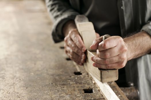 Hands of a carpenter planed wood, workplace