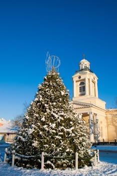 Christmas tree covered with snow and the church in the background