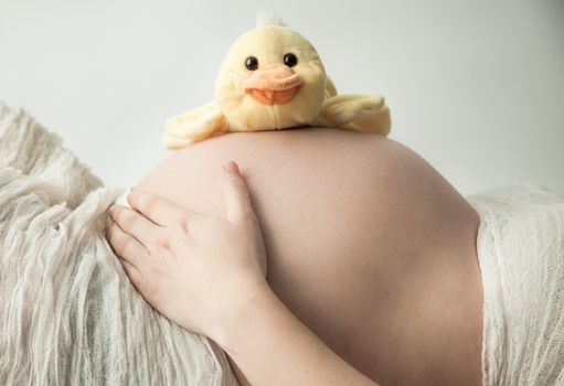 Pregnant belly lying with small duck