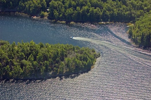 Small boat tracks on surface of water in sunlit