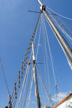 Ropes, sail and masts on blue sky background