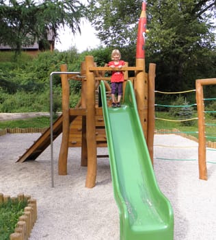 Photo of a child what is at a playground on the slide.