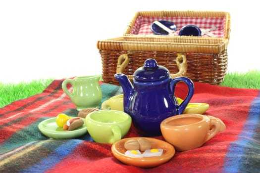 Picnic basket and dishes on a picnic blanket