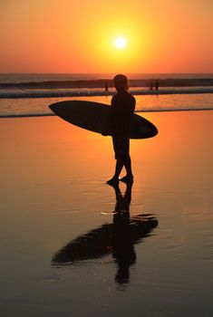 Silhouette of surfer with a board on a sunset