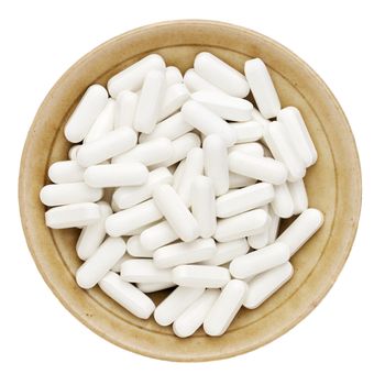 white vitamin, supplement  or drug pills in a small ceramic bowl