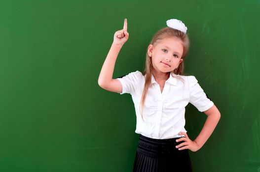 schoolgirl portrait near the blackboards, points finger up