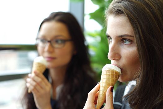 happy smiling women on foreground licking ice cream 