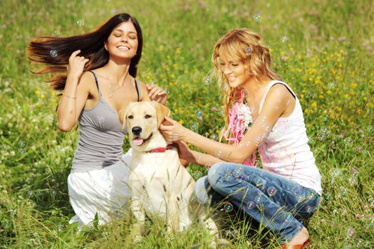 girlfriends and dog in green grass field